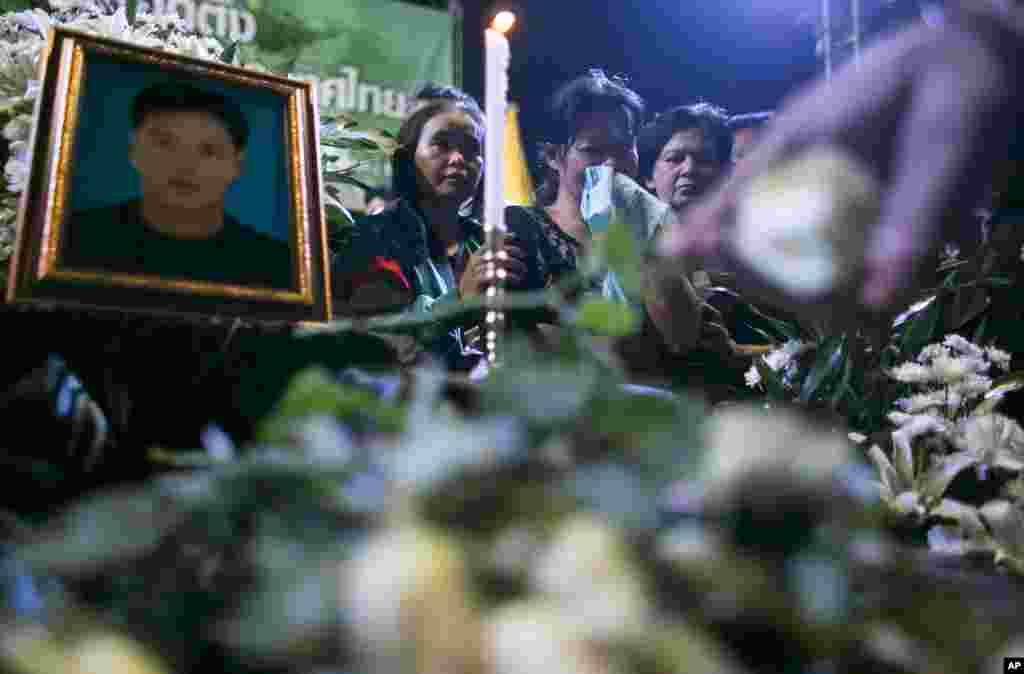 Thai anti-government protesters mourn in front of the picture of Yuthana Ong-art, who was shot and killed on Friday night, during a condolence ceremony in Bangkok, Thailand.