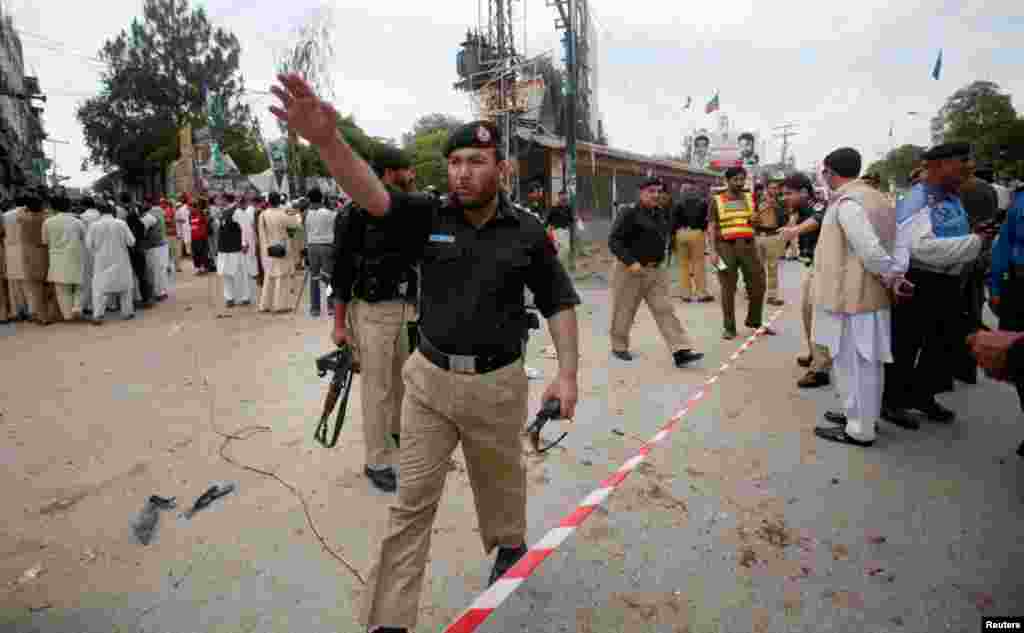 A police officer waves away onlookers at the site of the bomb blast in Peshawar.