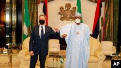 In this photo released by the Nigeria State House, U.S. Secretary of State Antony Blinken, left, is welcomed by Nigeria's President Muhammadu Buhari, right, before a meeting at the Presidential palace in Abuja, Nigeria, Nov. 18, 2021. 
