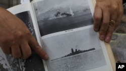 Filipino World War II historian Professor Rico Jose shows pictures before the Japanese World War II battleship Musashi sank as he talks to reporters at his office in suburban Quezon city, north of Manila, Philippines on Thursday, March 5, 2015.