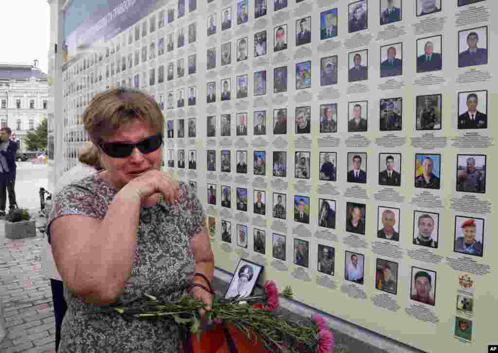 A woman cries at a memorial wall with photos of servicemen killed in the conflict with pro-Russian separatists in the country&#39;s east, in Kyiv, Ukraine.