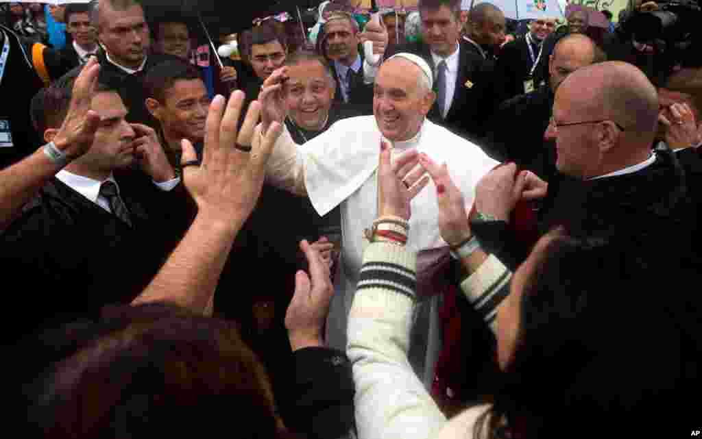 Warga menyambut Paus Fransiskus saat ia mengunjungi daerah kumuh Varginha di Rio de Janeiro, Brazil (25/7). (AP/Victor R. Caivano)