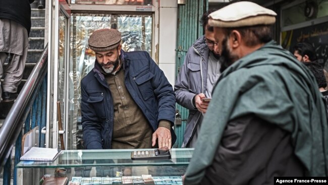An Afghan man looks at the currency notes on display at a money exchange shop in Kabul on Dec. 20, 2021.