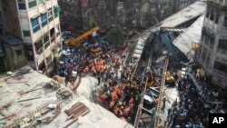 Residentes y rescatistas tratan de despejar escombros del colapsado puente en Kolkata, India.