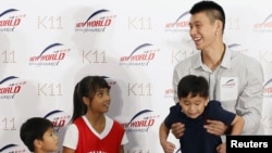 NBA basketball player Jeremy Lin (R) of the Houston Rockets holds up a child during a promotional event in Hong Kong August 24, 2012. Lin arrived in Hong Kong on Wednesday for his five-day Hong Kong tour. 