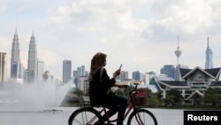 A woman rides a bicycle at a park, amid the coronavirus disease (COVID-19) pandemic, in Kuala Lumpur, Malaysia, Sept. 27, 2021. 