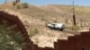 The view from the Mexican side as a U.S. Border Patrol car passes a fence. (G. Flakus/VOA)