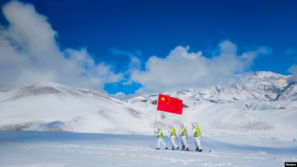 FILE - Auxiliary police and police officers in protective suits patrol the snow-covered border region in Ili Kazakh Autonomous Prefecture, Xinjiang Uyghur Autonomous Region, China, October 7, 2021. (China Daily via REUTERS)