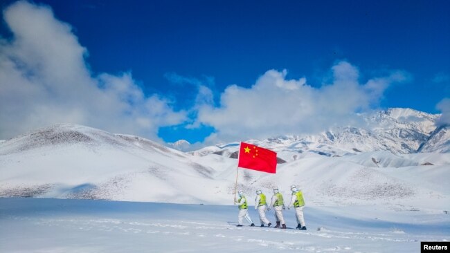 FILE - Auxiliary police and police officers in protective suits patrol the snow-covered border region in Ili Kazakh Autonomous Prefecture, Xinjiang Uyghur Autonomous Region, China, October 7, 2021. (China Daily via REUTERS)