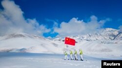 Auxiliary police and police officers in protective suits patrol the snow-covered border region in Ili Kazakh Autonomous Prefecture, Xinjiang Uyghur Autonomous Region, China, October 7, 2021.