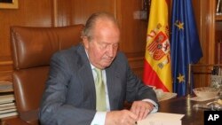 Sur cette photo publiée par le Palais royal, le roi Juan Carlos d'Espagne signe un document dans le Palais de la Zarzuela ouvrant la voie à son abdication, le 2 Juin 2014.