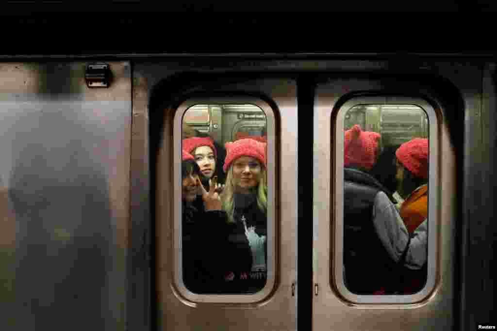 A group of people wearing "pussyhats" ride the subway at 42nd Street as they head toward the Women's March in Manhattan, New York City, New York.