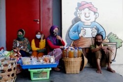 Para pedagang kaki lima mengenakan masker wajah di sebuah pasar di Bali di tengah wabah virus corona, 17 April 2020. (Foto: AP)