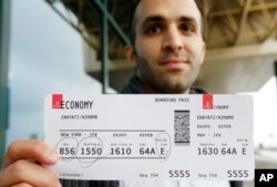 Iranian-born bioengineer researcher Nima Enayati holds up his boarding pass at the Milan's Malpensa International airport in Busto Arsizio, Italy, Feb. 5, 2017.
