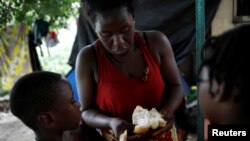 An African migrant spreads peanut butter on bread for children in Tapachula, Mexico, May 15, 2019. 