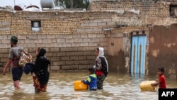 FILE - An Iranian family walks through a flooded street in a village around the city of Ahvaz, in Iran's Khuzestan province, March 31, 2019.