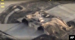 FILE - In this photo made from the footage taken from Russian Defense Ministry official website April 7, 2017, an aerial view shows shelters for aircraft at a Syrian air base after it was hit by U.S. strike in Syria.