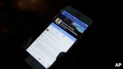 FILE - A man views then-Cambodian Prime Minister Hun Sen's Facebook page on his mobile phone along a sidewalk in downtown Phnom Penh, Cambodia.