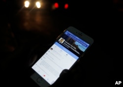 FILE - A man views Cambodian Prime Minister Hun Sen's Facebook page on his mobile phone at a side walk in downtown Phnom Penh.