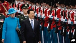 资料照：2012年6月14日，中国时任国家主席胡锦涛在对丹麦进行国事访问期间与丹麦女王玛格丽特二世在丹麦哥本哈根机场检阅女王的卫队。（美联社）