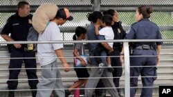Ever Castillo, kiri, dan keluarganya, imigran dari Honduras, dikawal untuk kembali meninggalkan perbatasan AS oleh agen Patroli Perbatasan AS hari Kamis, 21 Juni 2018 di Hidalgo, Texas (foto: AP Photo/David J. Phillip)