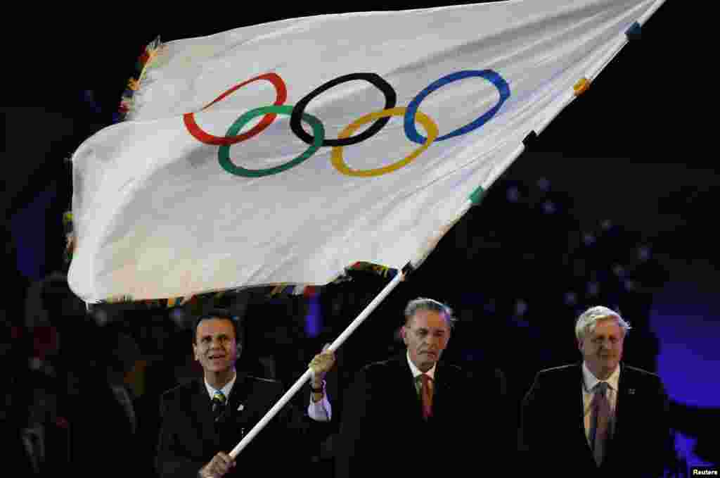 Rio de Janeiro Mayor Eduardo Paes (L) waves the Olympic Flag with IOC President Jacque Rogge (C) and London Mayor Boris Johnson (R) during the closing ceremony of the London 2012 Olympic Games at the Olympic Stadium, August 12, 2012.