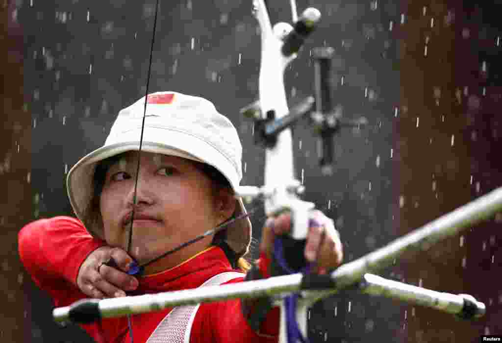 Fang Yuting de China apunta al blanco durante un evento de tiro con arco de mujeres, en el Lords Cricket Ground de Londres, mientras cae la lluvia.