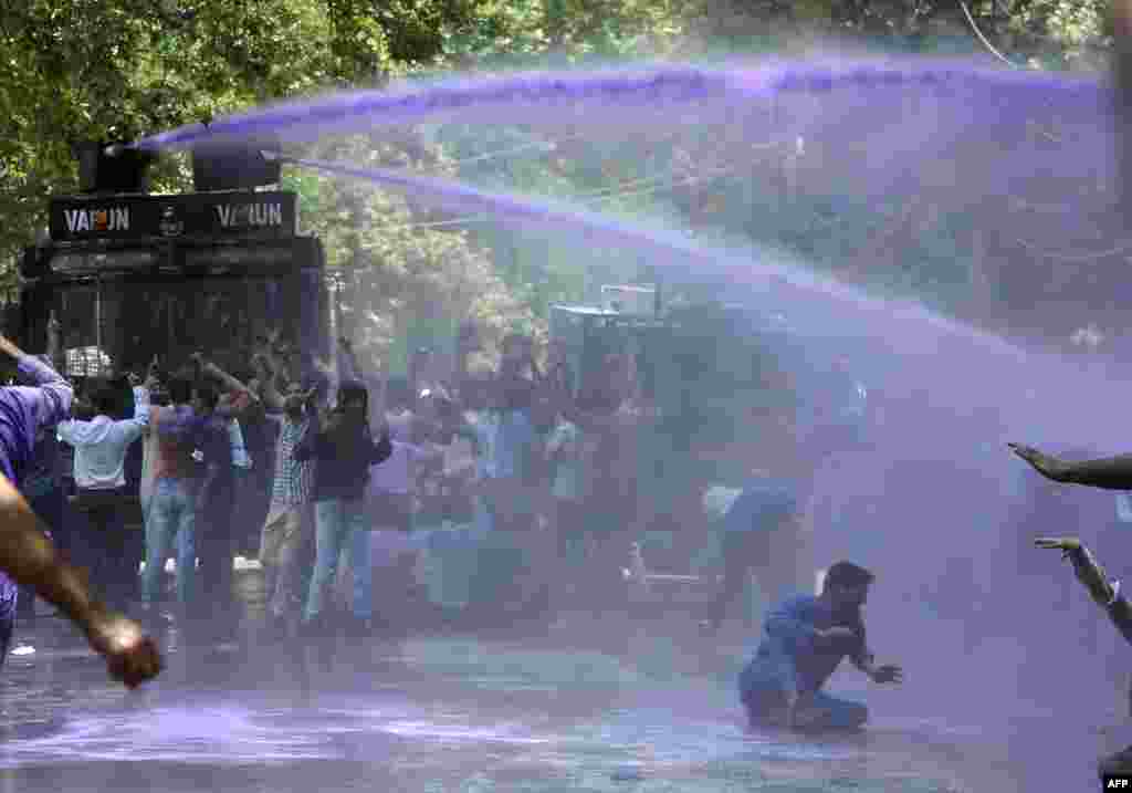Kashmiri government teachers shout anti-government slogans as Indian police spray purple colored water during a protest in Srinagar, India.