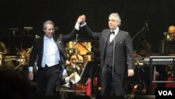 Andrea Bocelli, derecha, de la mano del director de la orquesta Eugene John durante el concierto en Washington. [Foto: Mitzi Macias, VOA].