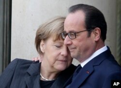 French President Francois Hollande embraces German Chancellor Angela Merkel, left, as she arrives at the Elysee Palace, Paris, Sunday, Jan. 11, 2015.