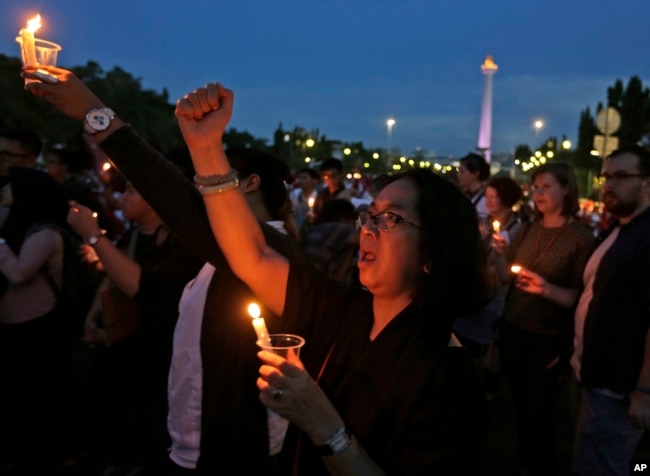 Seorang aktivis memegang lilin dan meneriakkan slogan-slogan saat berjaga untuk seorang gadis remaja yang diperkosa dan dibunuh oleh 14 pria di Bengkulu, di luar istana presiden di Jakarta. (Foto: AP)