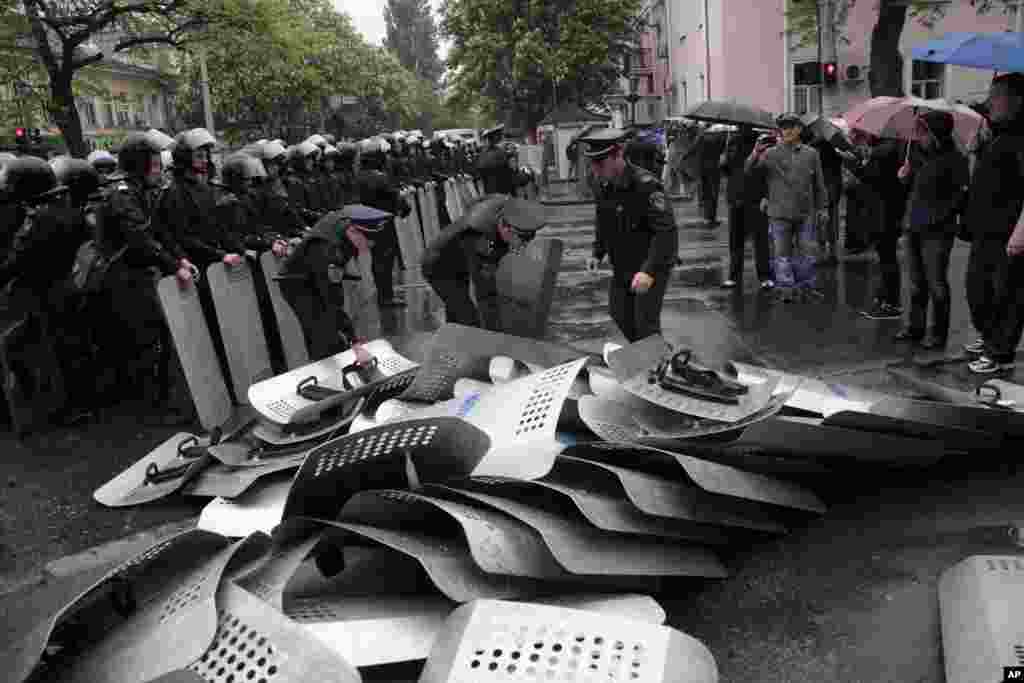 Ukrainian police officers remove shields which their comrades from another unit placed there earlier, outside police headquarters, in Odessa, May 4, 2014.