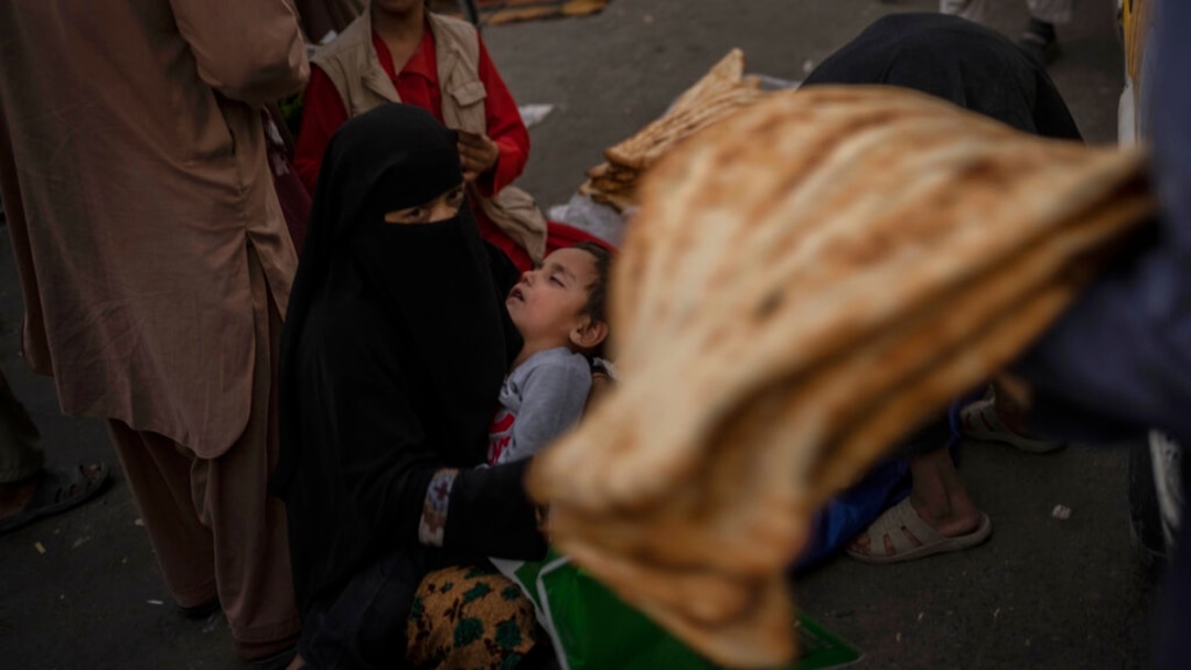 FILE - An Afghan woman begs at a market in Kabul's Old City, Afghanistan, Sept. 14, 2021.