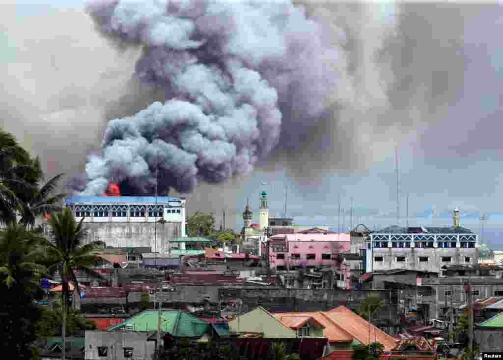 Black smoke billows from a burning building in a commercial area of Osmena street in Marawi city, Philippines.