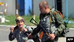 An armed pro-Russia separatist walks with a woman fleeing shelling near the train station in Donetsk, Ukraine, on July 21, 2014.