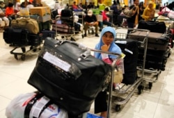 Seorang tenaga kerja perempuan Indonesia duduk di atas troli ketika menunggu berkas miliknya diperiksa saat tiba di Bandara Soekarno-Hatta dari Arab Saudi, pada 28 Oktober 2009. (Foto: Reuters/Beawiharta)