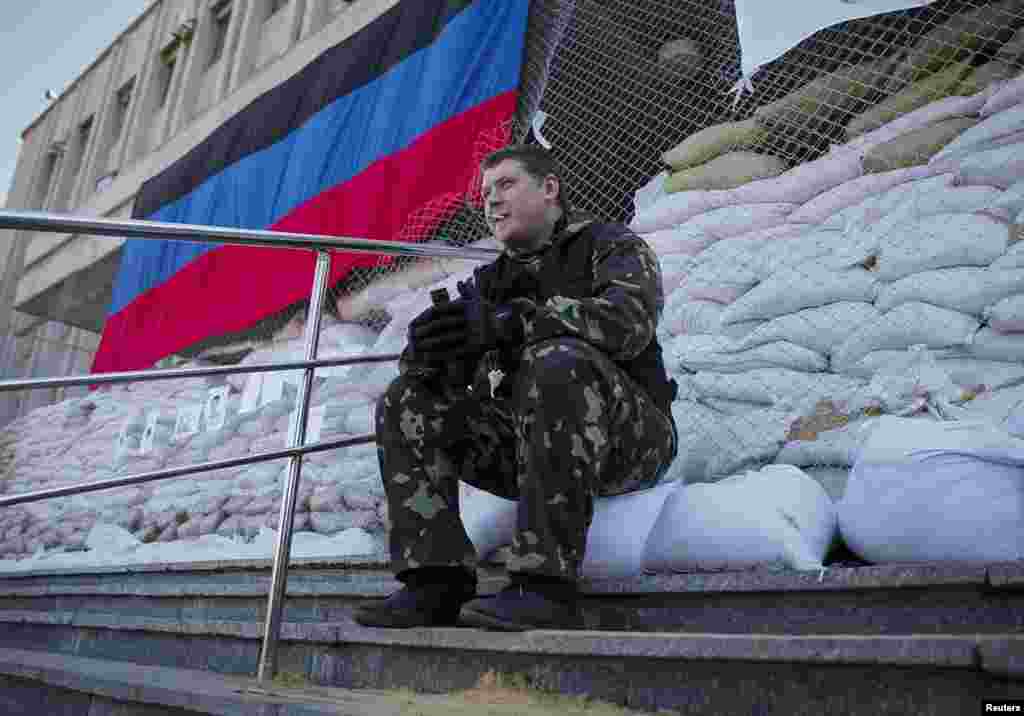 A pro-Russian armed man smokes as he guards near the mayor's office in Slovyansk, Ukraine, April 25, 2014. 