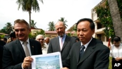 Cambodian official Han Touch (r) and German Embassy officer Adelbert Eberhardt hold a design of a memorial building as Joachim Baron Von Marschall, center, German Ambassador to Cambodia, watches at the building site, at the Tuol Sleng Genocide Museum, in in Phnom Penh, Cambodia, July 10, 2014. 