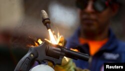 Un trabajador destruye un arma confiscada en Caracas.