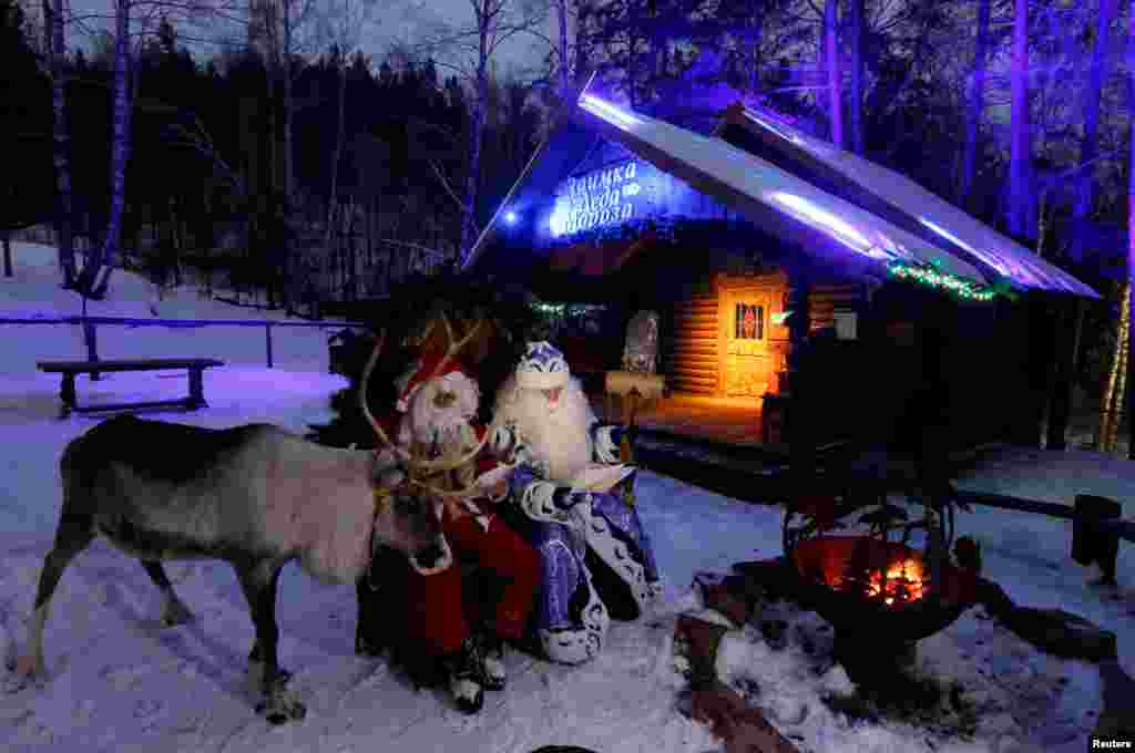 Two men, one dressed as Santa Claus, and the other as Father Frost — the Russian equivalent of Santa Claus — stage a performance for visitors at the Royev Ruchey Park in the suburbs of Krasnoyarsk, Russia.