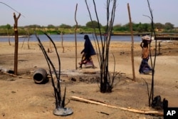 FILE - Chadian women walk past destroyed homes, in the Lake Chad shore village of N'Gouboua, March 5, 2015.