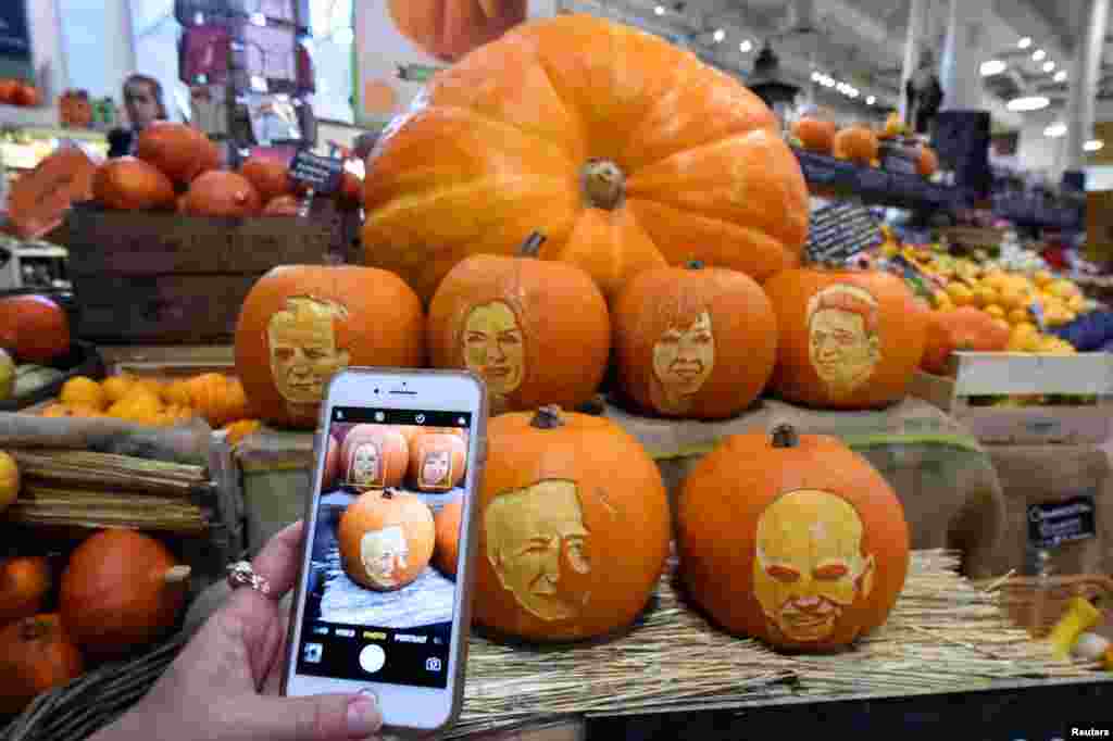 A woman takes a picture on her phone of Halloween pumpkins with Ireland&#39;s Presidential candidates faces carved into them in a shop ahead of an upcoming Presidential election in Dublin, Ireland.