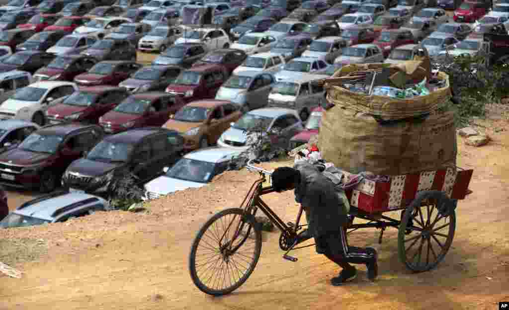 A ragpicker pushes his tricycle as Christians sit in their vehicles maintaining social distancing to prevent the spread of COVID-19 during a drive-in mass at Bethel AG Church in Bengaluru, India.