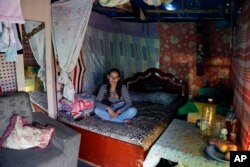 In this Tuesday, Dec. 12, 2017 photo, Renata Swiecik sits on a bed inside her shack