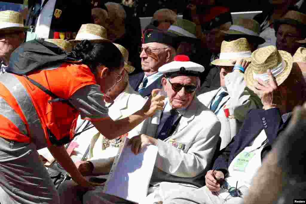 A Red Cross worker sprays water on a veteran during a ceremony in Boulouris, France, marking the 75th anniversary of the Allied landings in Provence in World War II, which helped liberate southern France.