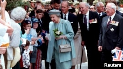 FILE - Queen Elizabeth (C) receives flowers and letters from the public as she walks with the Duke of Edinburgh (center rear) following a ceremony honoring World War II veterans in Wellington, New Zealand, Nov. 5, 1995.