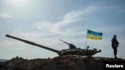 FILE - A Ukrainian soldier stands guard near a tank position close to the Russian border near Kharkiv.