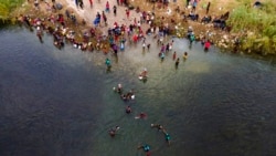 Migrants, many from Haiti, are seen wading between the U.S. and Mexico on the Rio Grande, in Del Rio, Texas, Sept. 21, 2021.