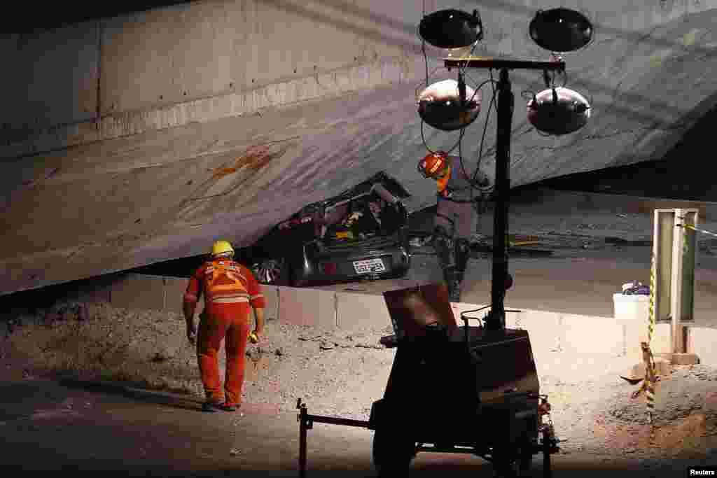 Regu penolong memeriksa sebuah mobil yang terperangkap di bawah jembatan yang ambruk saat masih dalam tahap pembangunan di Belo Horizonte (3/7).