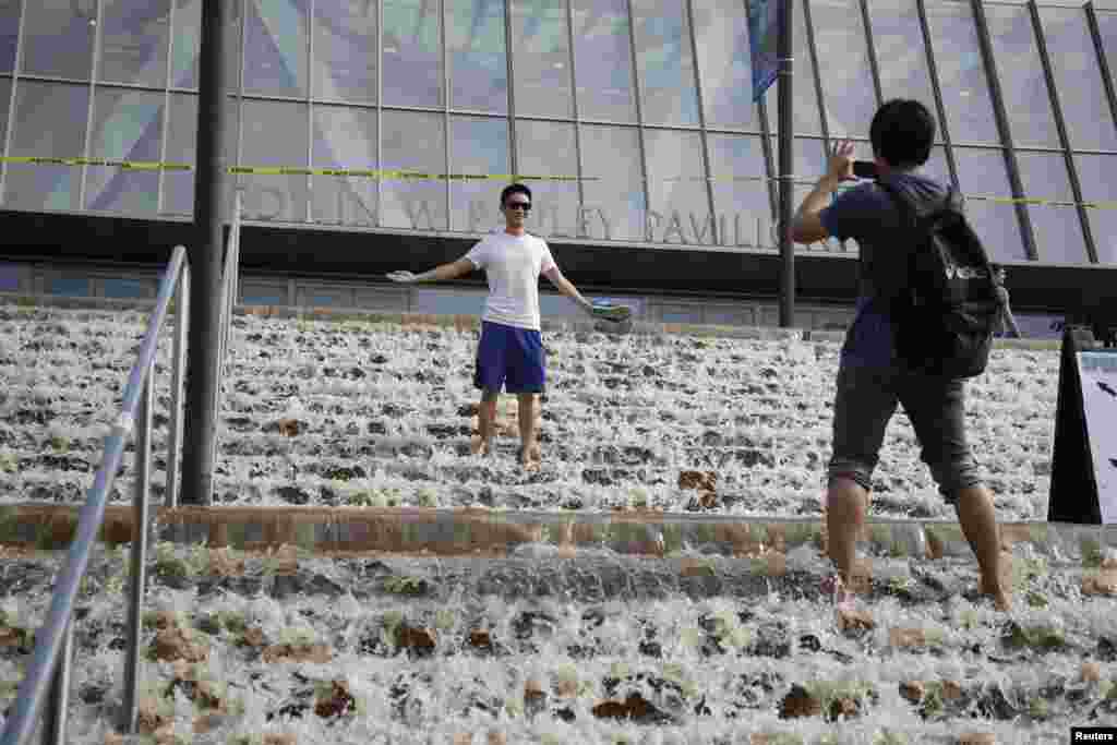 7月29日，一名男子在加州大学洛杉矶分校体育馆门前留影。由于总水管爆裂，学校体育馆门口出现&rdquo;瀑布&ldquo;景观。